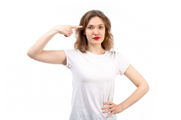 Una vista frontal jovencita en camisa blanca y jeans negros modernos posando en el blanco