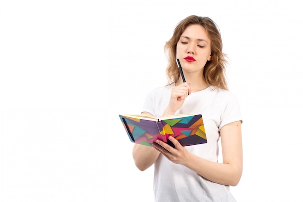 Una vista frontal jovencita en camiseta blanca escribiendo notas sobre el blanco