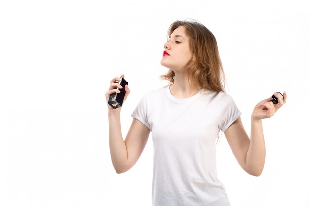 Una vista frontal jovencita en camiseta blanca con tubo de perfume negro sobre el blanco