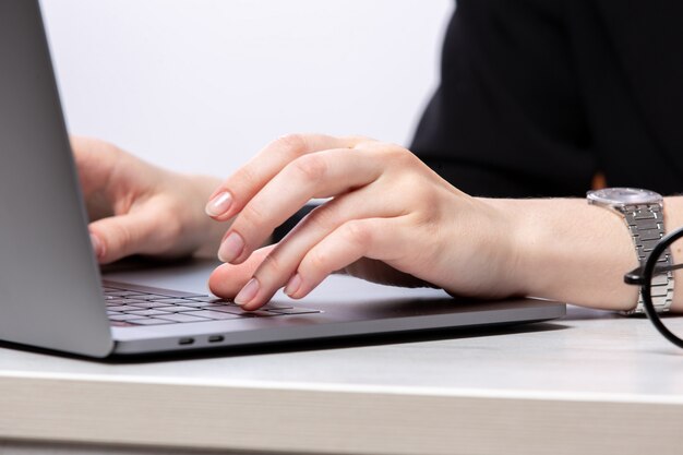 Una vista frontal jovencita usando su computadora portátil de trabajo de trabajo de plata