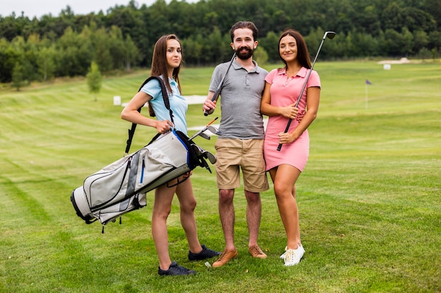 Foto gratuita vista frontal de jóvenes golfistas mirando a cámara