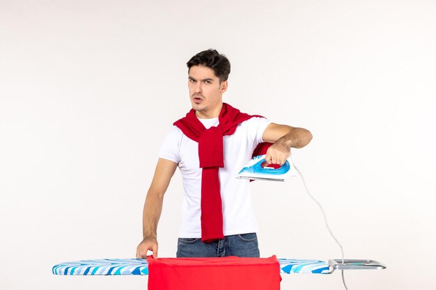 Vista frontal de los jóvenes varones preparándose para planchar una toalla sobre fondo blanco, limpiar las tareas del hogar, el trabajo a domicilio, la emoción, la moda, el hombre de ropa