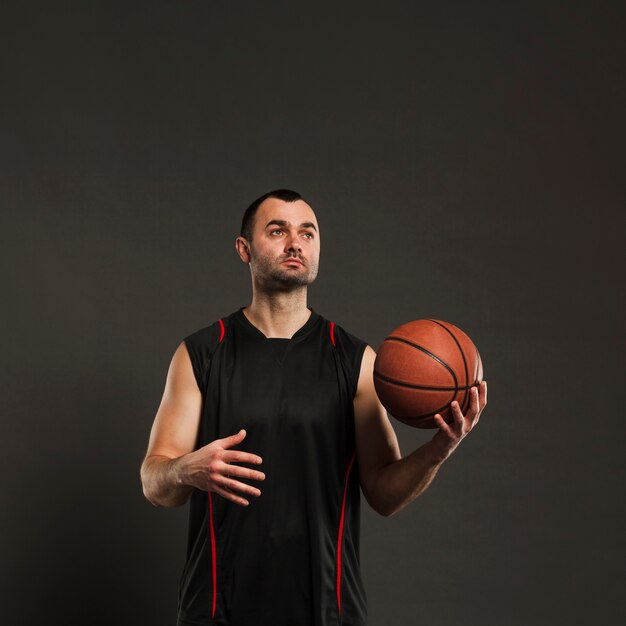 Vista frontal del jugador de baloncesto posando mientras lanza la pelota de una mano a la otra