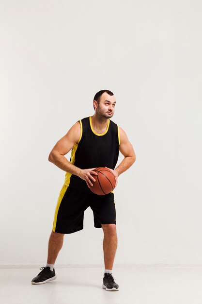 Vista frontal del jugador masculino a punto de saltar con baloncesto en manos