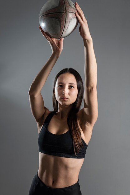 Vista frontal del jugador de rugby femenino posando con pelota