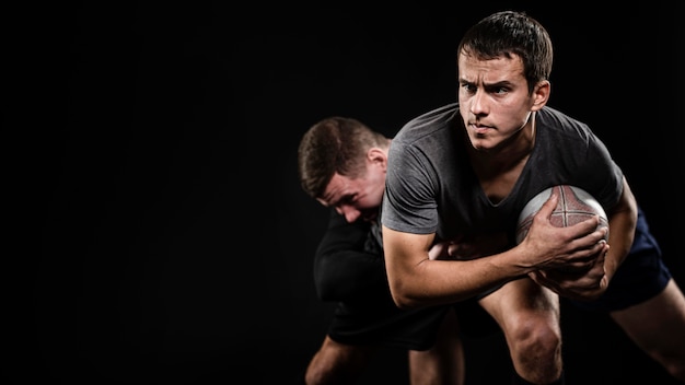 Vista frontal de jugadores de rugby masculinos con pelota y espacio de copia