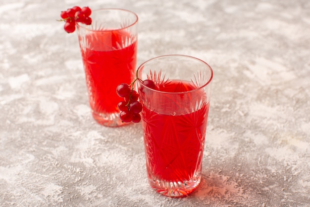 Vista frontal de jugo de arándano rojo dentro de vasos en un escritorio brillante