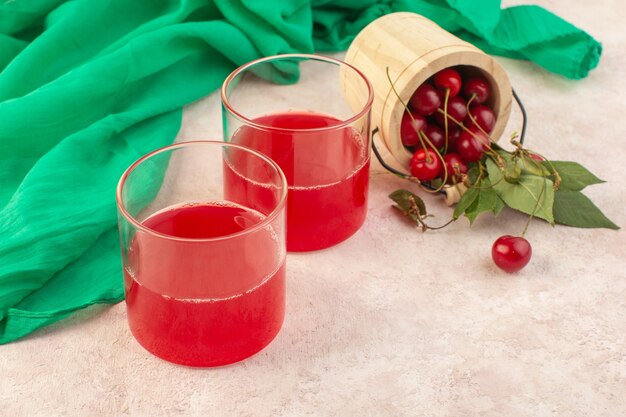 Una vista frontal de jugo de cereza roja con cerezas frescas en el cóctel de bebida de color de fruta de escritorio rosa