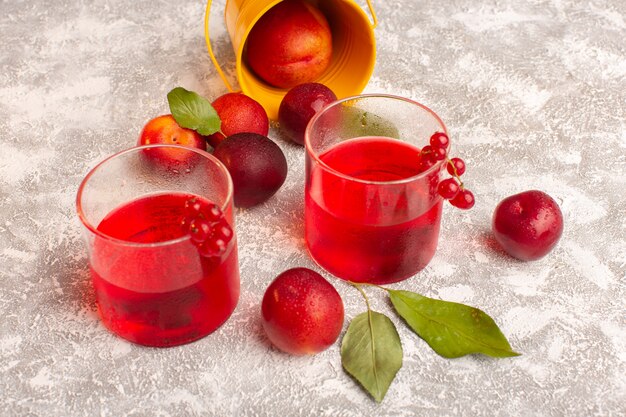 Vista frontal de jugo de ciruela roja con ciruelas frescas en bebida de jugo de color de fruta brillante