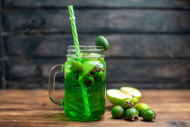 Vista frontal de jugo de feijoa verde dentro de lata en barra oscura cóctel de fotos en color de frutas