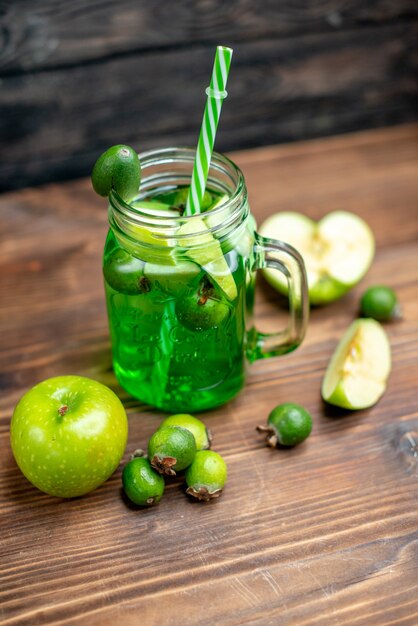 Vista frontal jugo fresco de feijoa dentro de lata con manzanas verdes en la barra oscura cóctel fotográfico de bebida de color de fruta