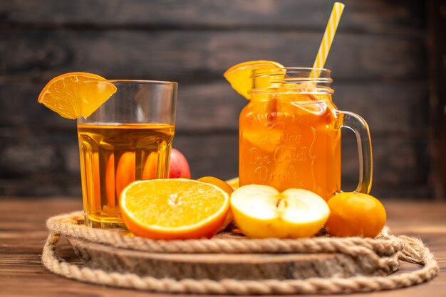 Vista frontal de jugo fresco orgánico en una botella y vaso servido con tubo y frutas en una tabla para cortar