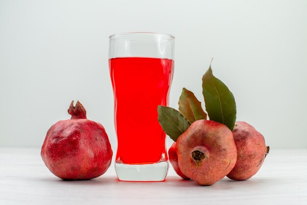 Vista frontal de jugo de granada fresca con frutas en la pared blanca bebida de jugo de fruta cóctel fresco