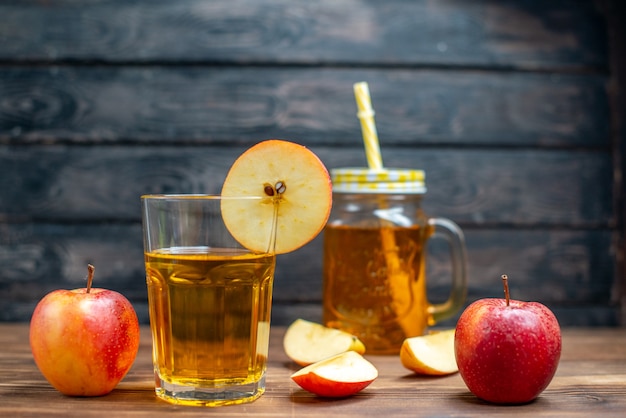 Vista frontal de jugo de manzana fresco con manzanas frescas en el color de la bebida de frutas de cóctel de fotos de escritorio de madera marrón
