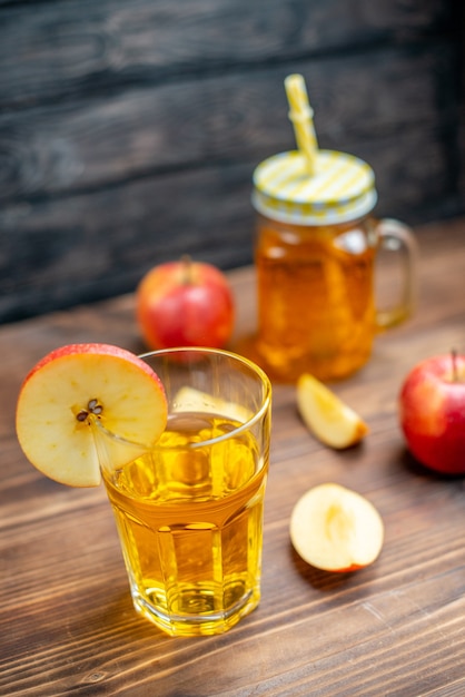 Vista frontal de jugo de manzana fresco con manzanas frescas sobre piso de madera marrón cóctel de fotos de color de bebida de frutas