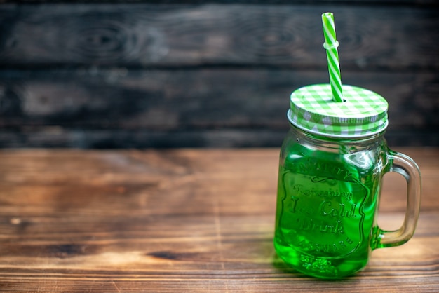 Vista frontal de jugo de manzana verde dentro de lata en el escritorio de madera bebida cóctel color fruta