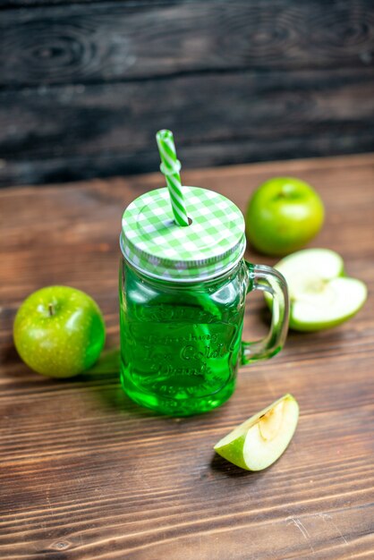 Vista frontal de jugo de manzana verde dentro de lata con manzanas frescas en el escritorio de madera, bebida de color de la foto de la fruta