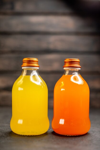 Vista frontal de jugo de naranja y amarillo en botellas