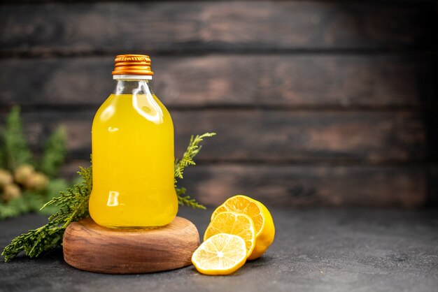 Vista frontal de jugo de naranja fresco en botella sobre tablero de madera