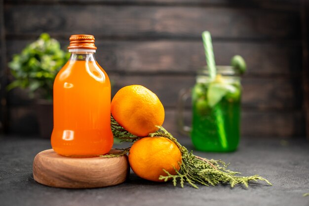 Vista frontal de jugo de naranja fresco en botella sobre tablero de madera