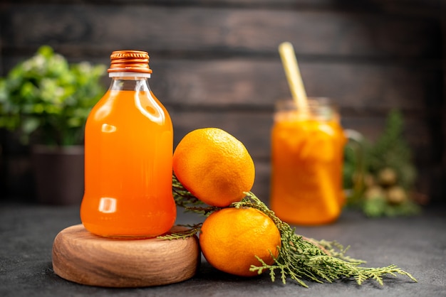 Vista frontal de jugo de naranja fresco en botella sobre tablero de madera