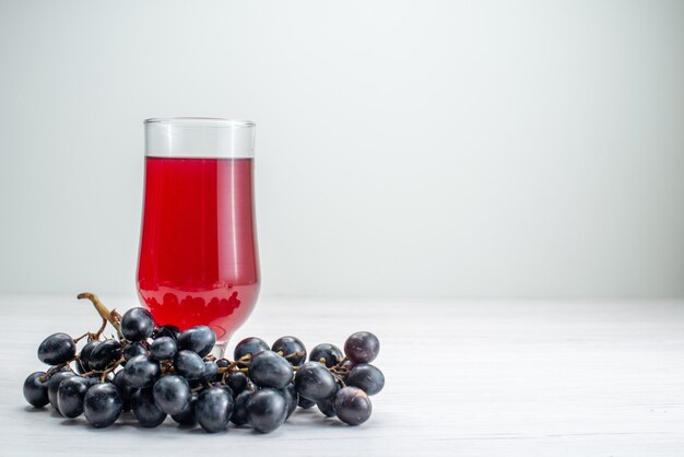 Vista frontal de jugo rojo con uvas en jugo de cóctel de bebida de fruta de superficie blanca