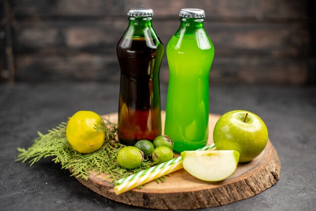 Vista frontal jugos negros y verdes en botellas pipetas de feijoas de limón y manzana sobre tablero de madera