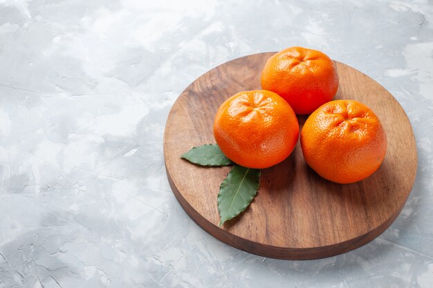 Vista frontal jugosas mandarinas frescas cítricos suaves de color naranja en el escritorio blanco cítricos tropicales exóticos