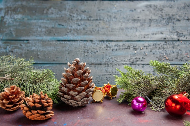 Vista frontal de juguetes navideños con conos y árbol en el escritorio oscuro árbol planta vacaciones navideñas