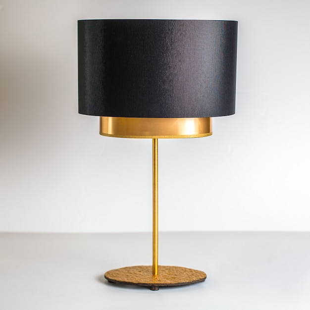 Una vista frontal de la lámpara de oro negro diseñada exquisitamente sobre el fondo blanco.