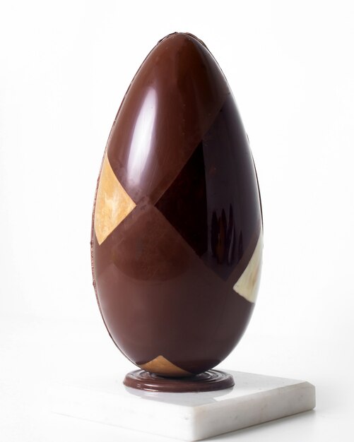 Vista frontal largo huevo marrón chocolate en el piso blanco