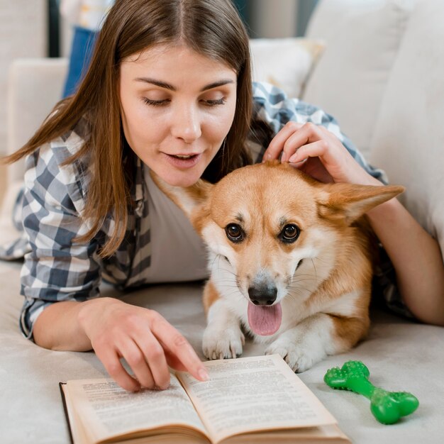 Vista frontal del libro de lectura de mujer con perro en el sofá