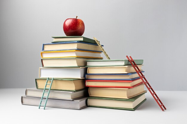 Vista frontal de libros apilados, escaleras y una manzana con espacio de copia para el día de la educación