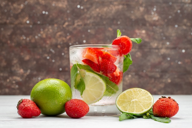 Foto gratuita vista frontal de lima y fresas frescas y suaves con un vaso de agua en blanco, fruta baya bebida cítricos tropicales