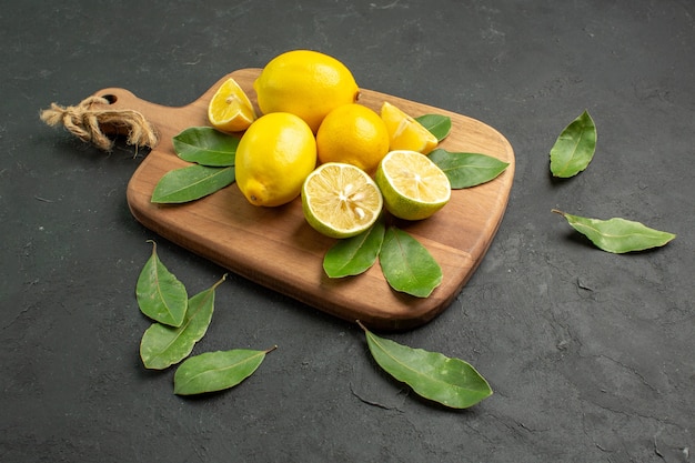 Vista frontal limones frescos frutos amargos sobre el fondo oscuro
