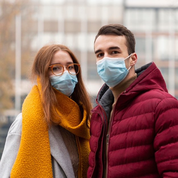 Vista frontal de la linda pareja con máscaras médicas