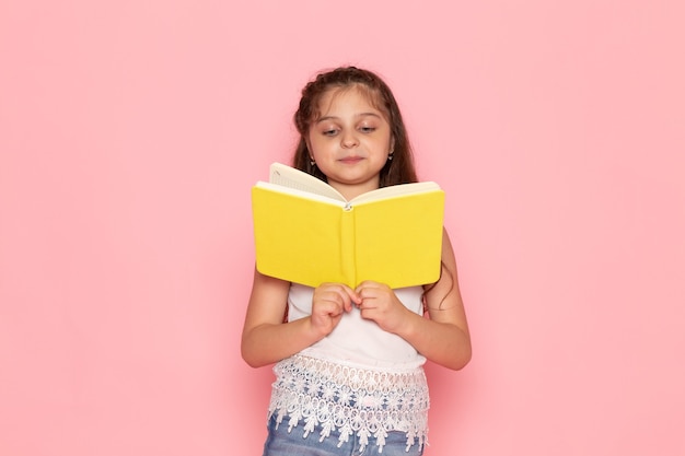 Una vista frontal lindo niño leyendo cuaderno amarillo