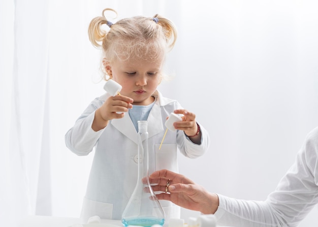 Vista frontal del lindo niño pequeño aprendiendo sobre ciencia con malvaviscos