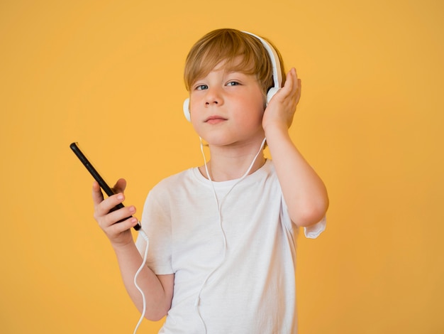 Vista frontal del lindo niño pequeño escuchando música