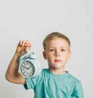 Foto gratuita vista frontal lindo niño sosteniendo un reloj