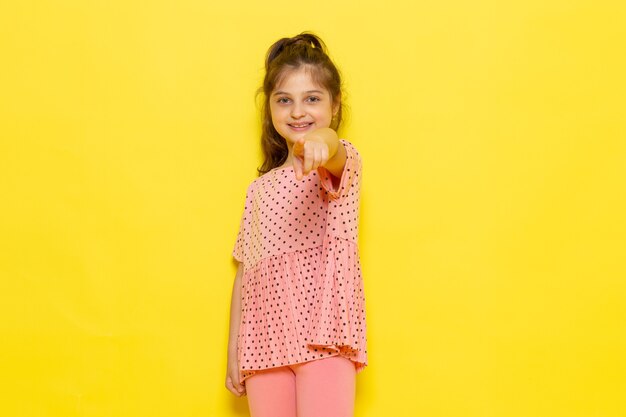 Foto gratuita una vista frontal lindo niño en vestido rosa sonriendo y señalando