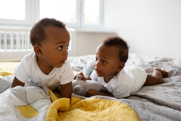 Vista frontal lindos bebés acostados en la cama