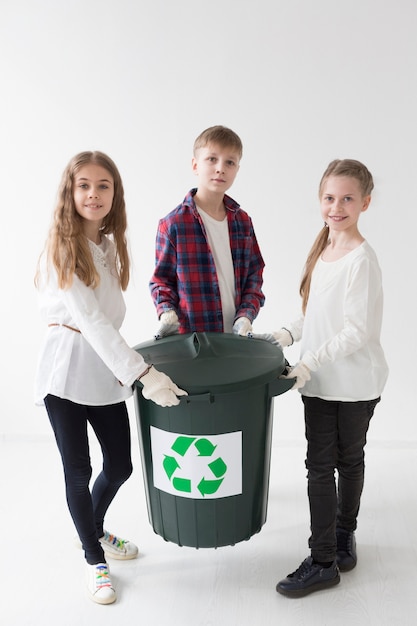 Vista frontal lindos niños pequeños felices de reciclar