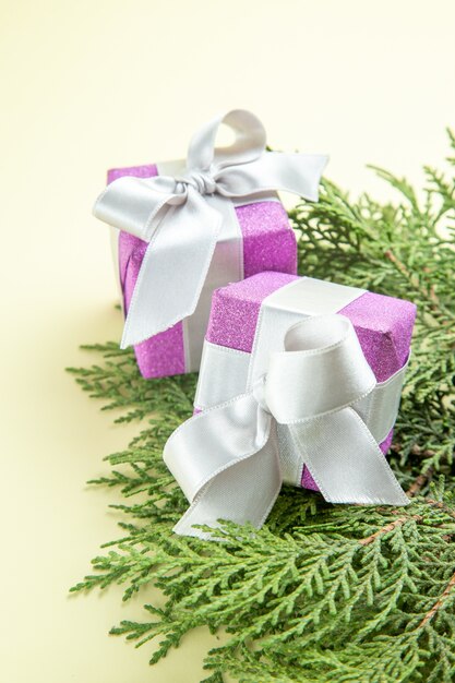 Vista frontal lindos pequeños regalos con ramas verdes en mesa blanca