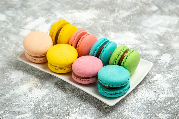 Vista frontal de macarons franceses coloridos pasteles sobre superficie blanca pastel pastel de azúcar hornear galletas galletas dulces