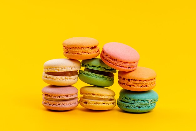 Una vista frontal macarons franceses deliciosos redondos aislados en amarillo, confitería de galletas de pastel