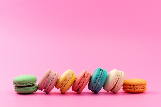 Una vista frontal macarons franceses redondos deliciosos coloridos aislados en rosa, confitería de galletas de pastel
