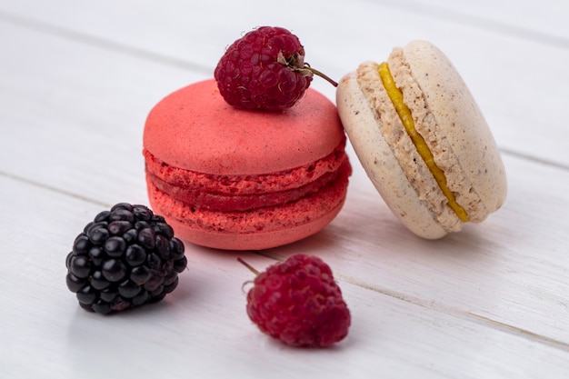 Vista frontal de macarons con moras y frambuesas sobre una superficie blanca