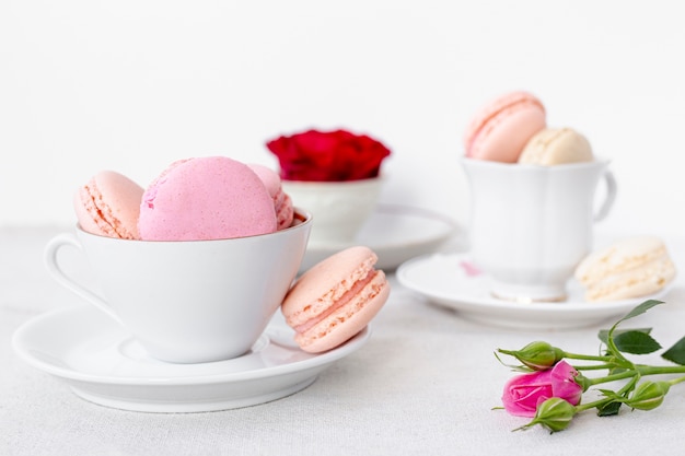 Foto gratuita vista frontal de macarons tazas con rosa