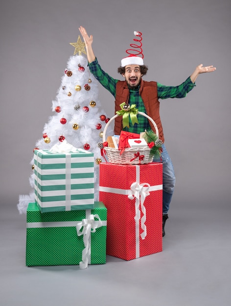 Vista frontal macho joven alrededor de regalos de vacaciones en la luz